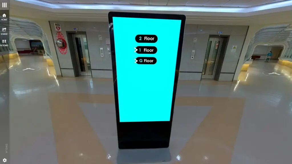 A preview of a virtual experience showing a digital information kiosk in a modern building displays directional arrows for floors labeled as 2, 1, and G. Two elevators are in the background on a shiny, reflective floor.